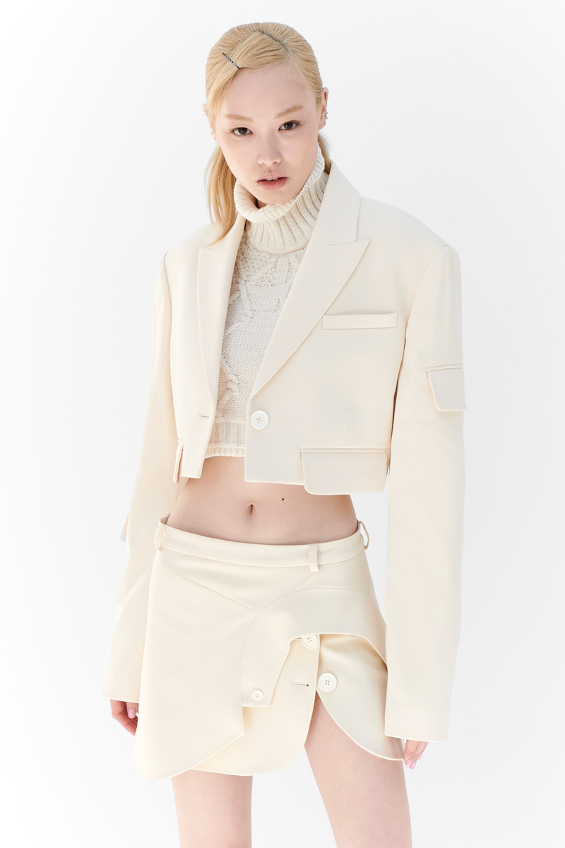 MONSE Resort 2024 Collection Vogue image of model wearing a white cropped turtleneck with short white mini skirt
