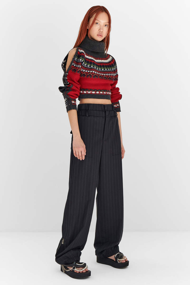 MONSE Resort 2024 Collection Vogue image of model wearing a red argyle sweater with black striped trousers
