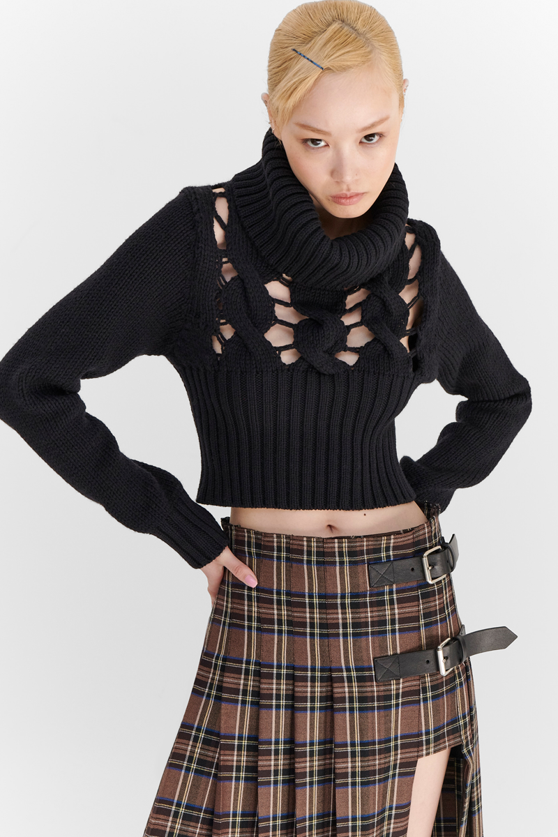 MONSE Resort 2024 Collection Vogue image of model wearing a black turtleneck sweater with a checkered skirt
