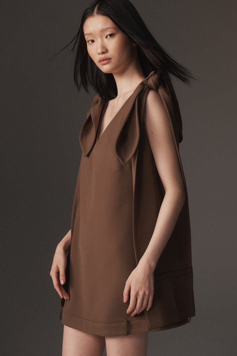 MONSE Resort 2026 collection lookbook image of a model wearing a brown dress against a dark background