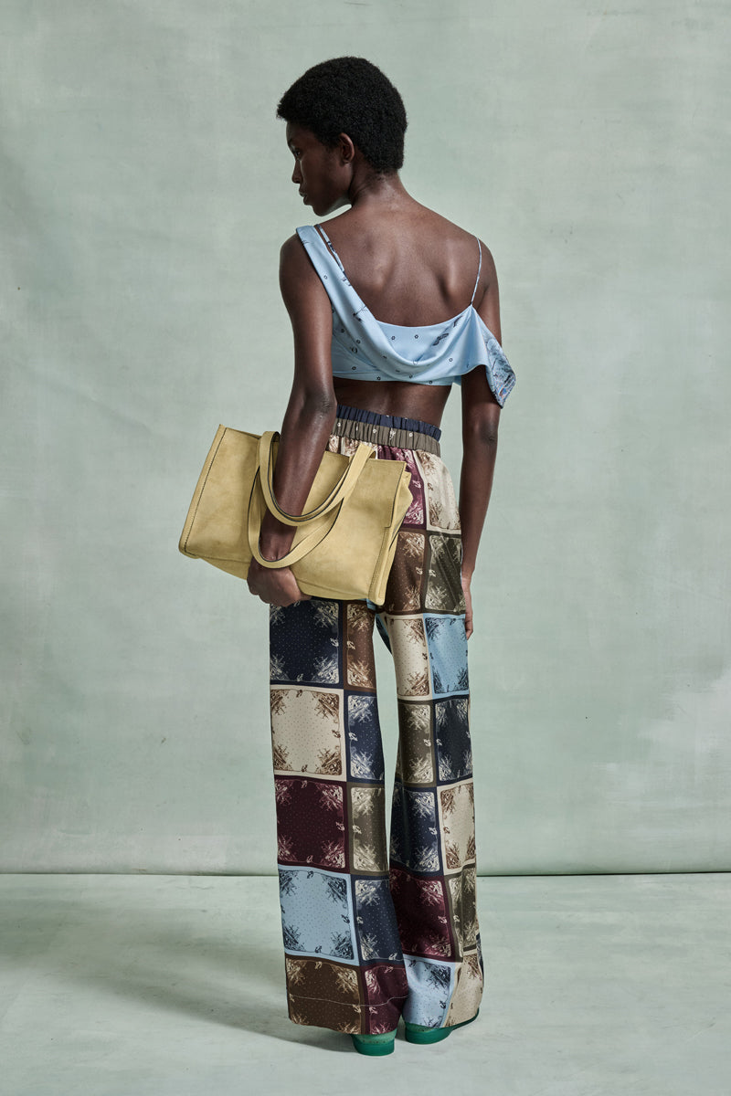 MONSE Spring 2026 Collection look 18 woman wearing a patterned outfit with a yellow bag on a plain background