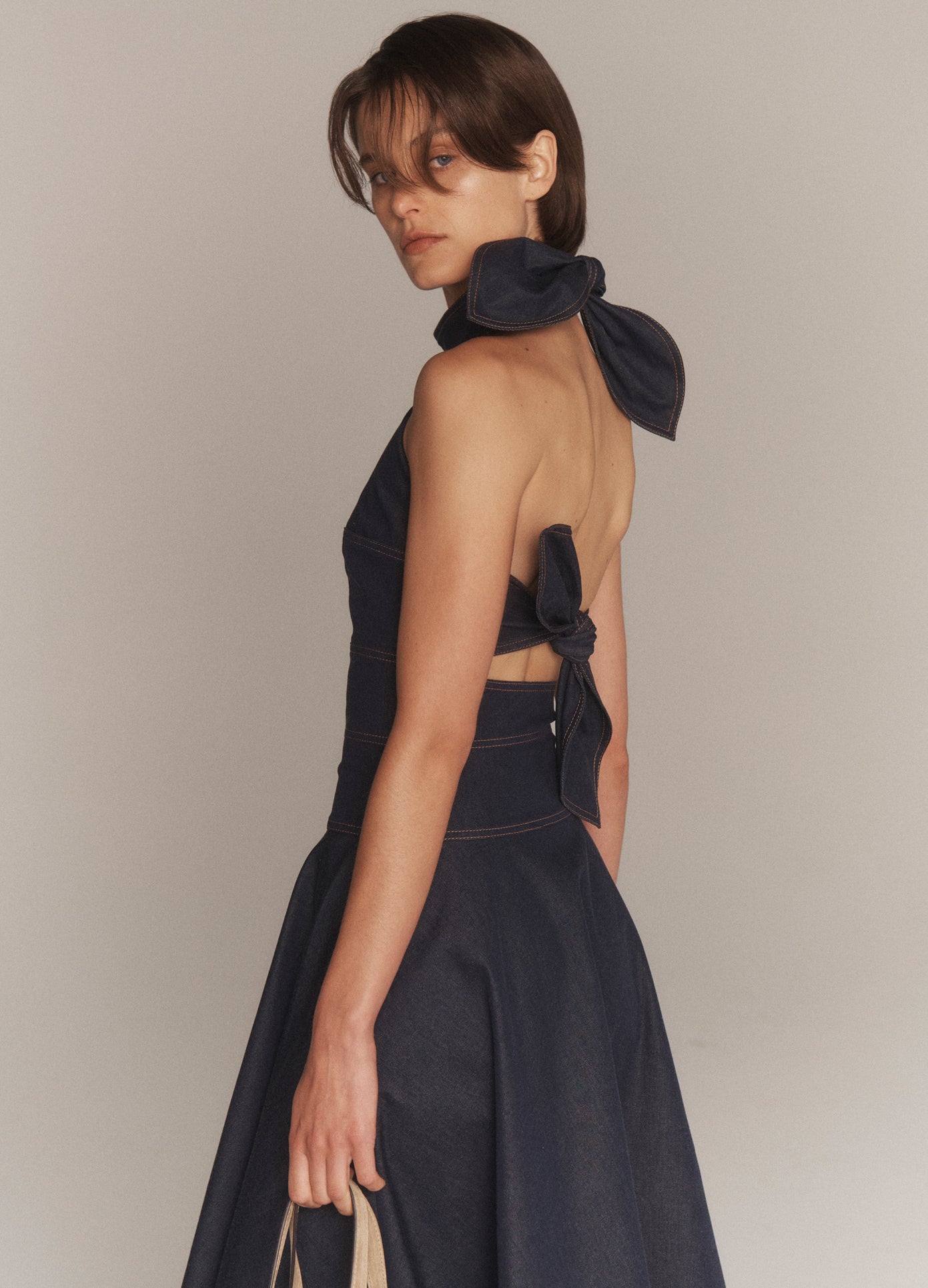 MONSE Back Bow Tie Midi Dress in dark indigo on model looking over shoulder side view