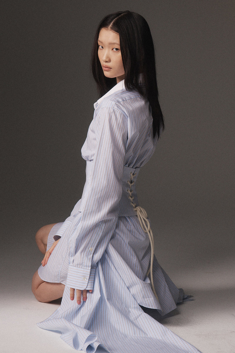 MONSE Resort 2026 collection lookbook image of a model wearing a light blue striped dress against a gray background
