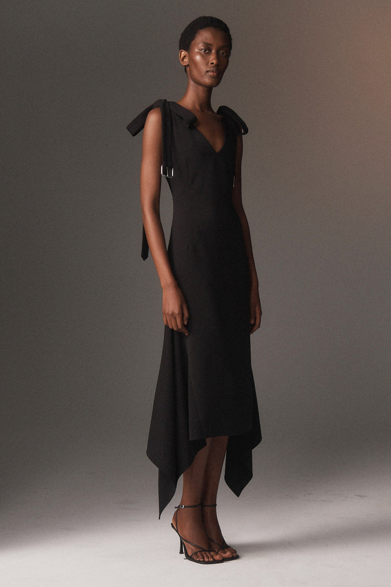 MONSE Resort 2026 collection lookbook image of a model wearing a black dress with ruffled shoulders against a neutral background