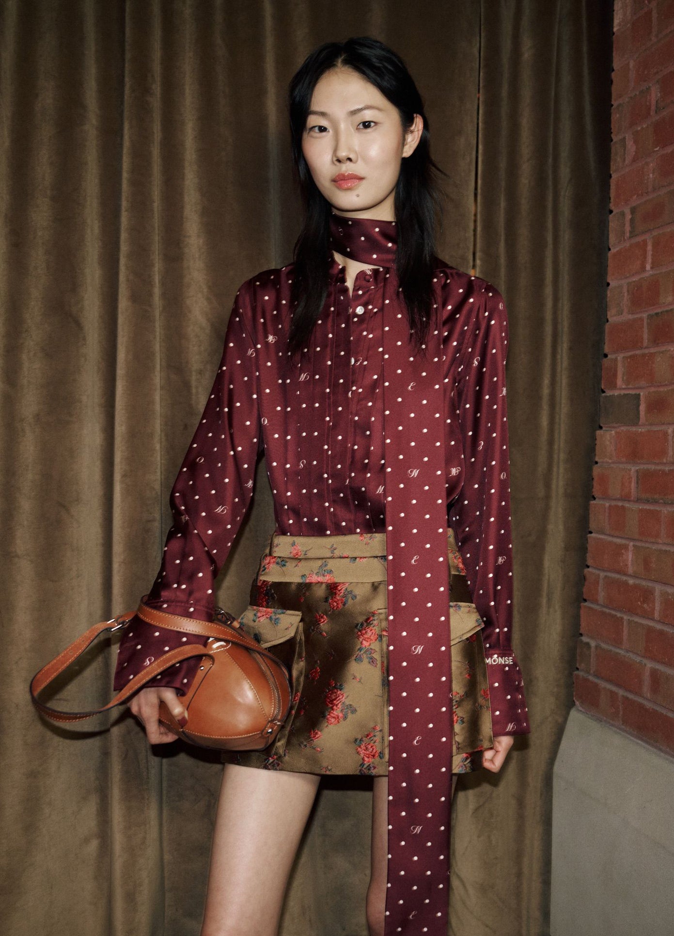 MONSE Tie Neck Cowl Back Blouse in burgundy on model backstage