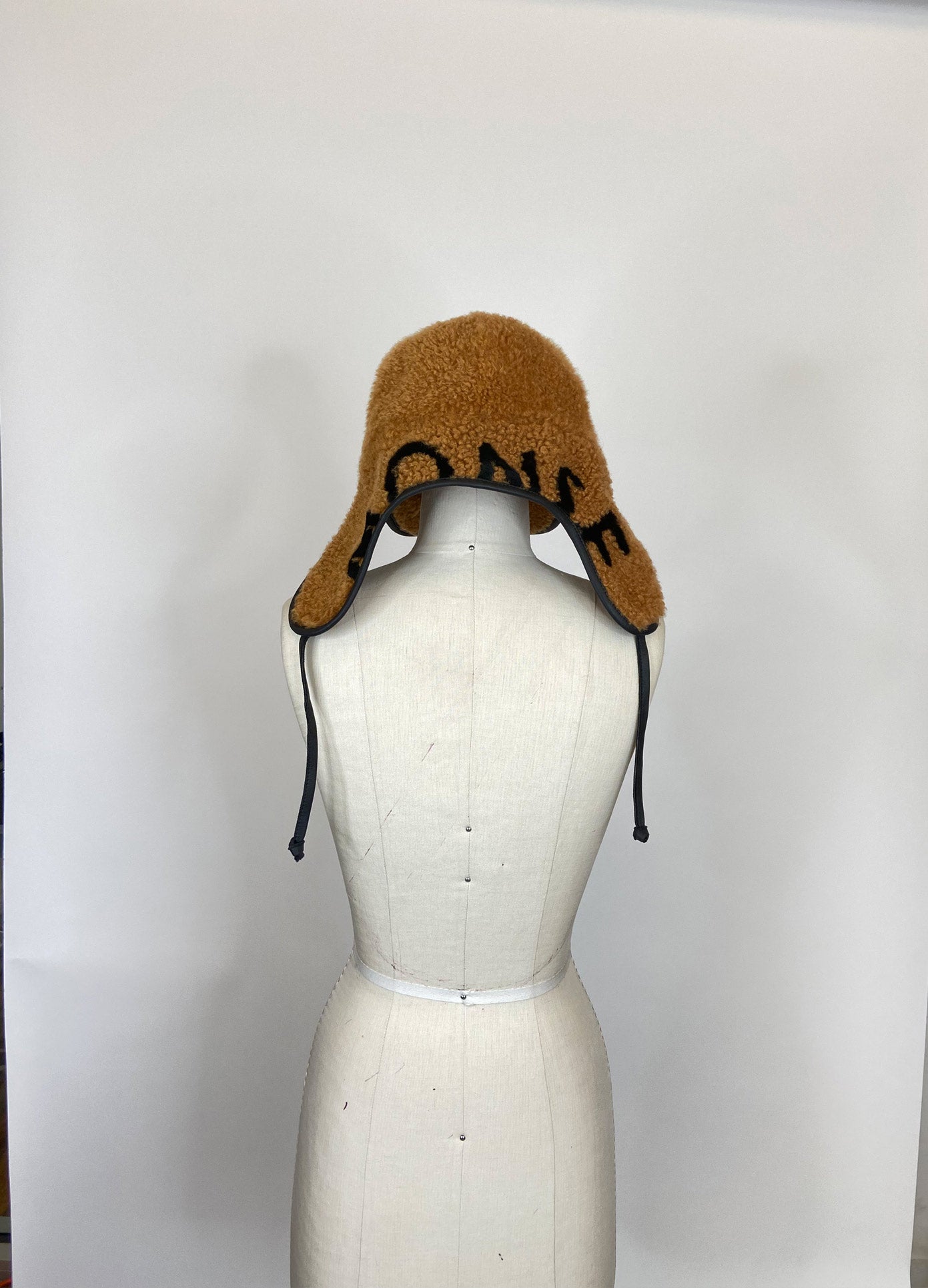 MONSE Cap with Ear Cover in Brown and Black on Mannequin Back View