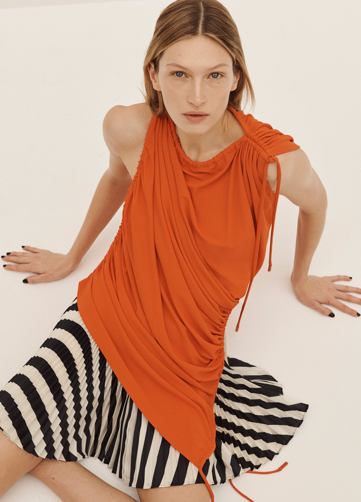 MONSE Drawstring Blouse in Orange on Model Sitting on the Ground Aerial View